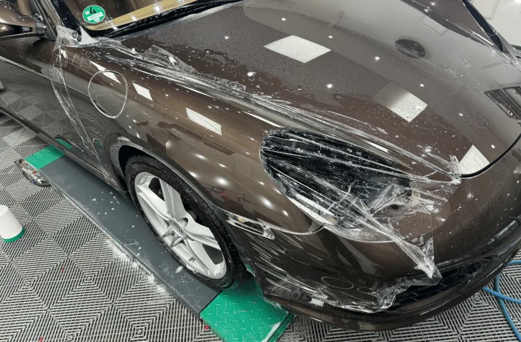 Porsche Boxster maro în timpul aplicării foliei PPF pe aripa față și în jurul farului