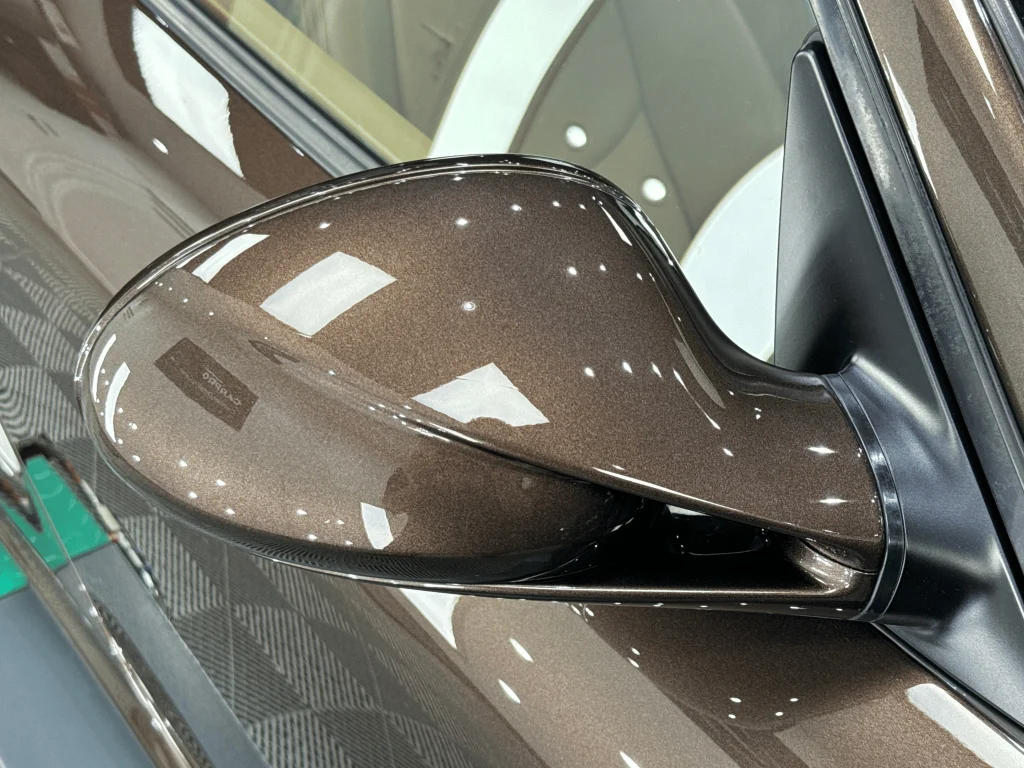 Oglinda laterală a unui Porsche Boxster maro, după aplicarea foliei PPF
