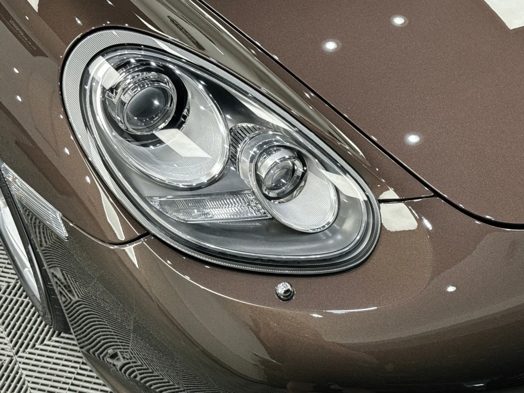 Farul unui Porsche Boxster maro, acoperit cu folie PPF transparentă