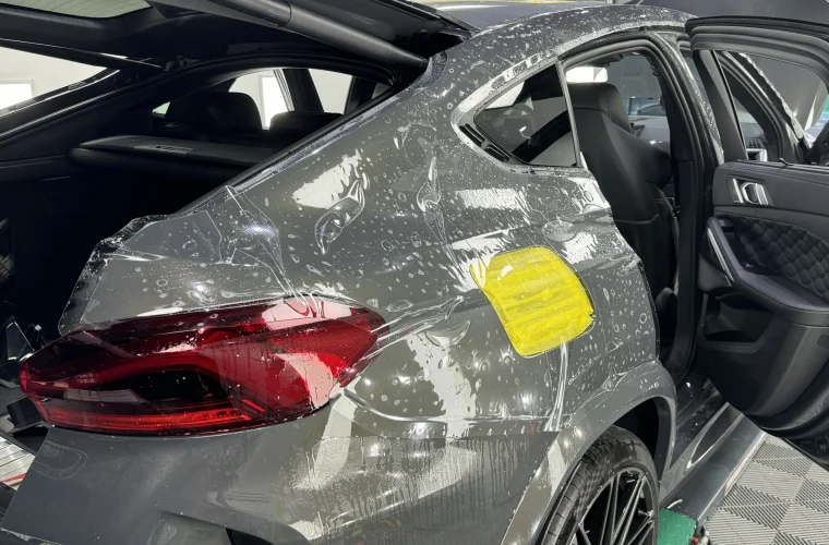Folie PPF în timpul aplicării pe aripa spate a unui BMW X6M gri