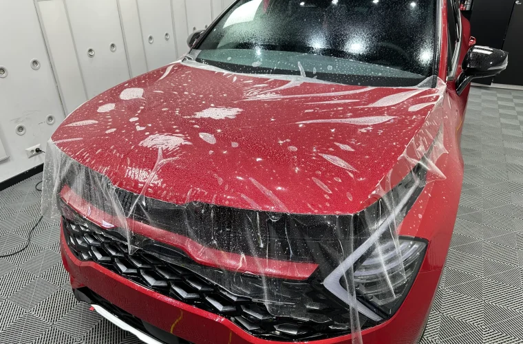 Kia Sportage roșu, cu folia PPF întinsă peste capotă și bara față